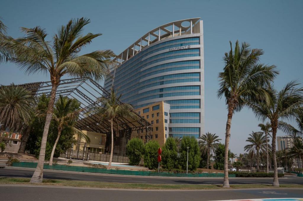 Un edificio alto con palmeras delante. en Seafront Luxury Suites Jeddah Corniche, en Yeda