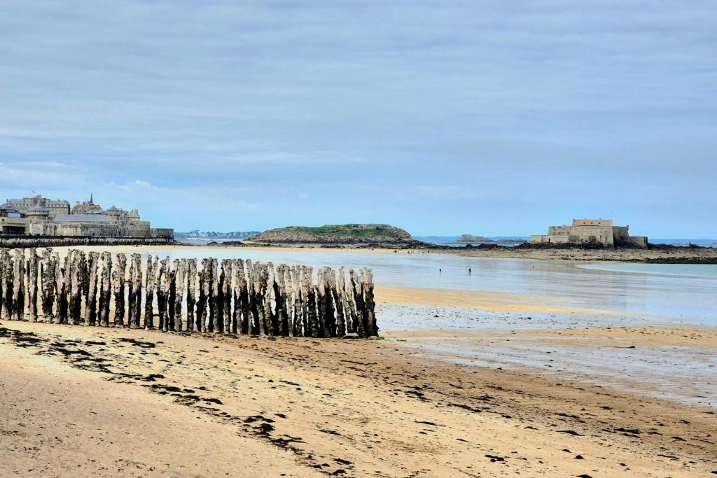 une plage avec une clôture en bois dans l'eau dans l'établissement Bright duplex with magnificent sea views, à Saint-Malo