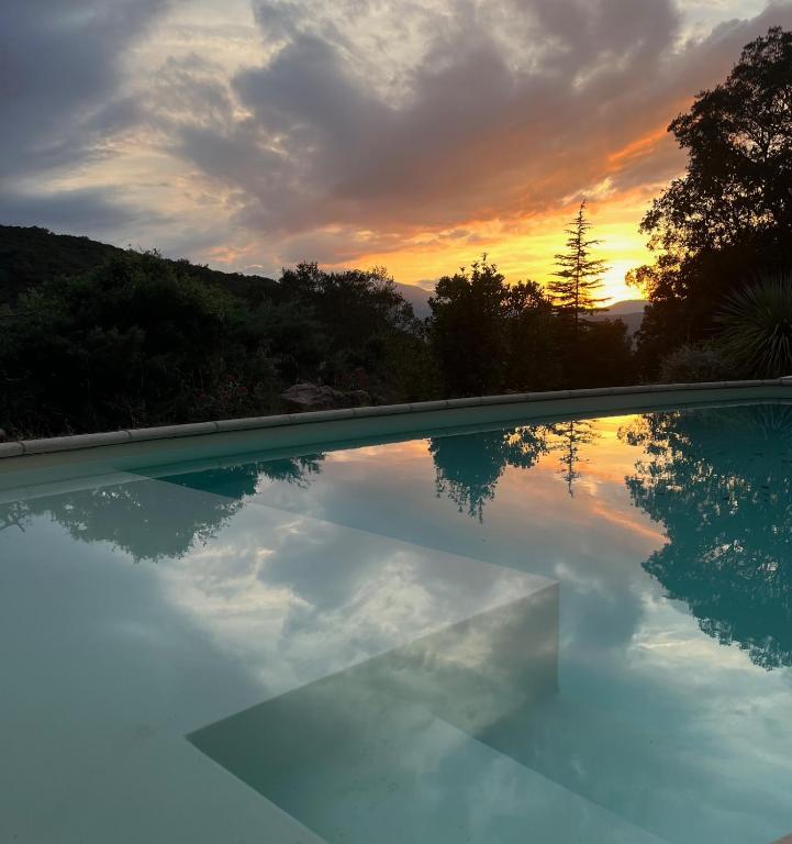 une piscine avec un coucher de soleil en arrière-plan dans l'établissement La Bonne Alt 303m, à Céret
