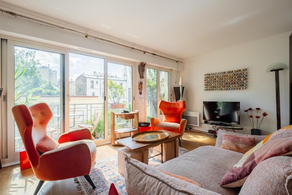 un salon avec un canapé et une télévision dans l'établissement Veeve - Safari Glade, à Paris