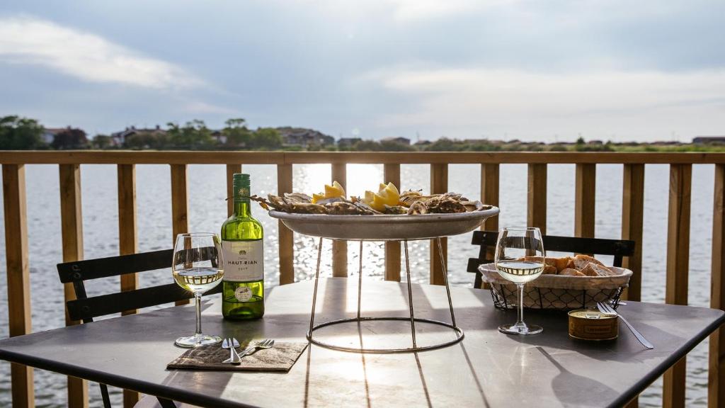 - une table avec deux verres de vin et un bol de fruits dans l'établissement Cabane bois bord de l'eau, à Gujan-Mestras