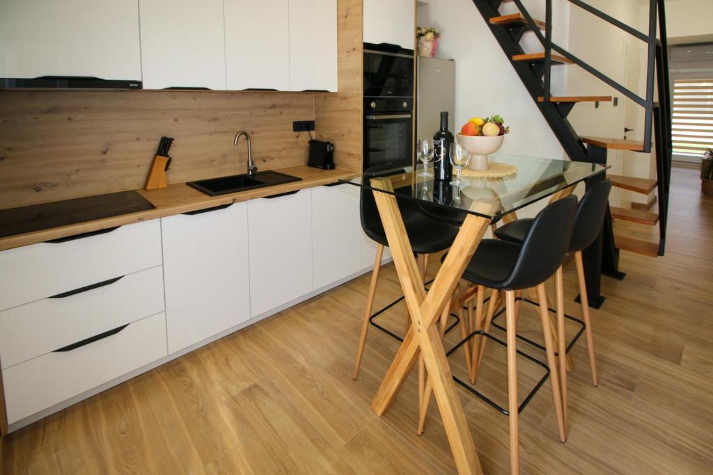 a kitchen with white cabinets and a glass table at Family House Bubalo in Opuzen