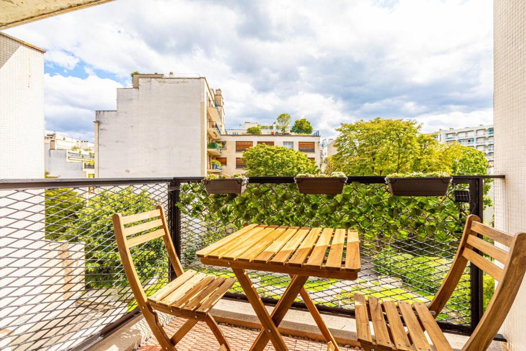 une table en bois et deux chaises sur un balcon dans l'établissement GuestReady - Homely nest with balcony, à Paris