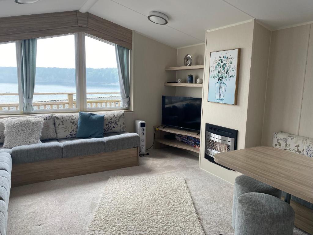 a living room with a couch and a television at Static Caravan at Lydstep Beach in Tenby