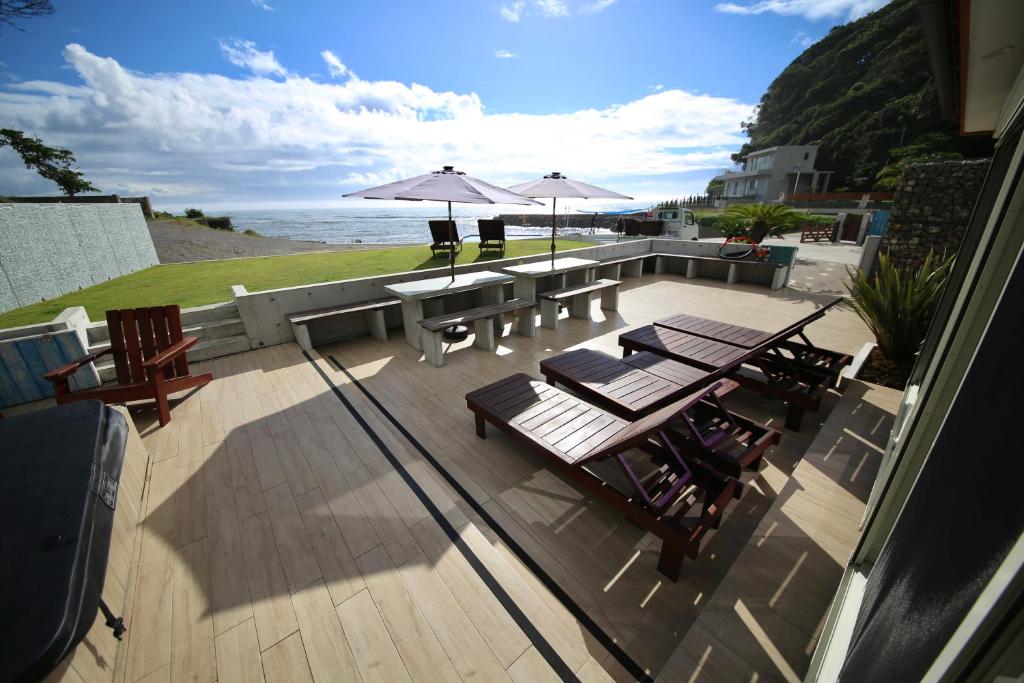 une terrasse avec tables de pique-nique et parasols donnant sur l'océan dans l'établissement ビーチキャビン - シービュー バーベキュー ピザ サウナ プール ホットタブ - Beach Cabin Chiba - Seaview BBQ Pizza Sauna Pool Hot-tub, à Kobama