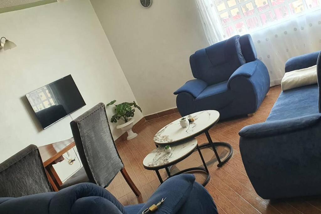a living room with blue chairs and a table at Talaa Comforts Homes in Eldoret