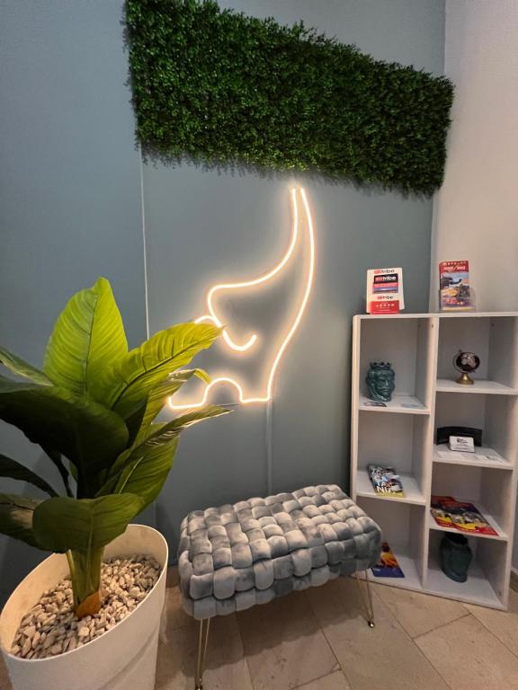 una stanza con una pianta e un'insegna al neon sul muro di Alta Dimora b&b suites a Catania