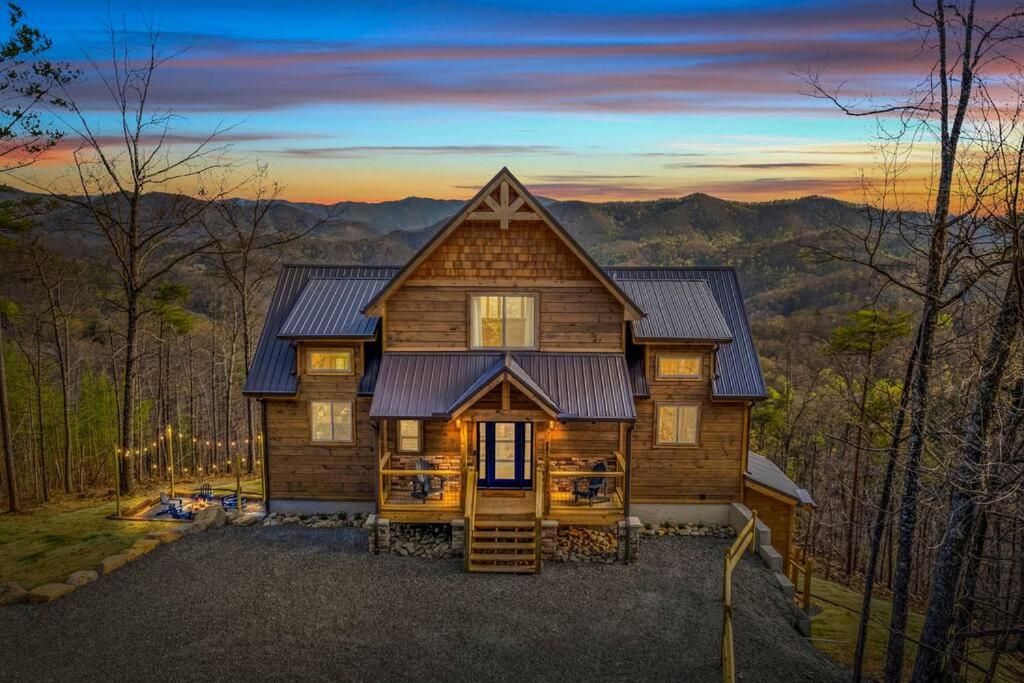 Una cabaña de troncos en el bosque al atardecer en Luxury Endless View 3 King Suites Billards Pool, en Sevierville