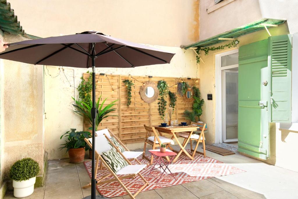 un patio avec un parasol, une table et des chaises dans l'établissement Paradis d'amour avec terrasse, à Marseille