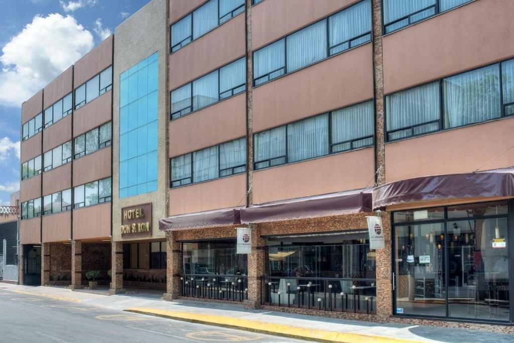 a large brick building with windows on a street at Hotel Don Simón in Toluca
