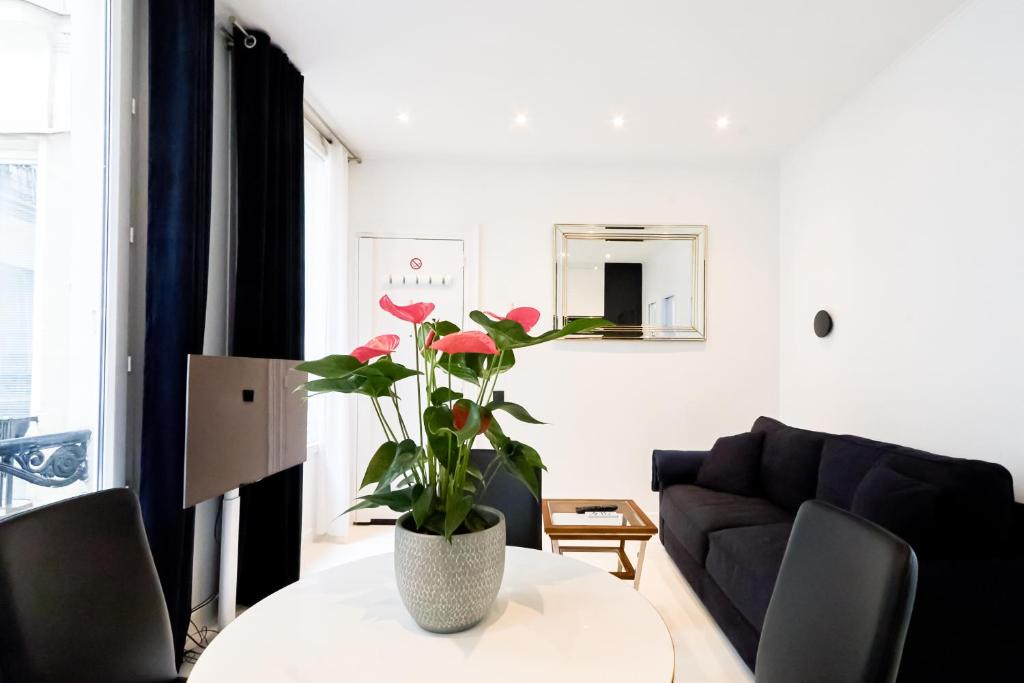 un salon avec une table et un vase avec des fleurs rouges dans l'établissement Champs-Élysées Executive Apartment, à Paris
