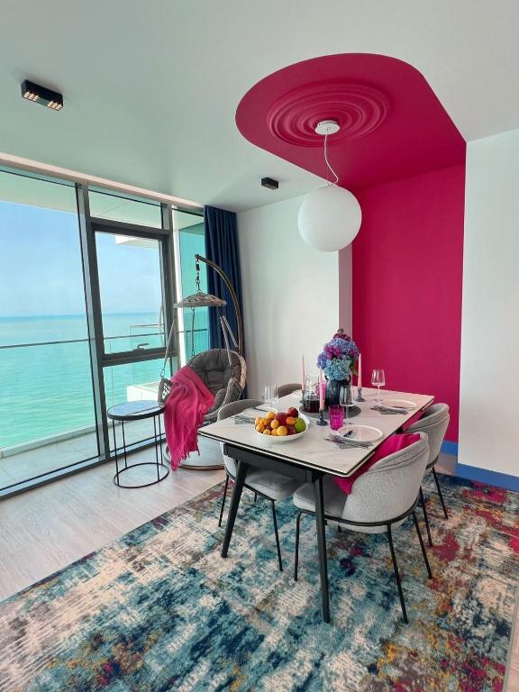 a dining room with a table and a pink wall at Apartment Batumi Weekend in Batumi