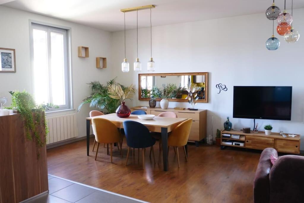 un salon avec une table, des chaises et une télévision dans l'établissement Cosy Bella appartement proche PartDieu, à Villeurbanne