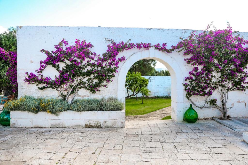 an arch with purple flowers on a wall at Masseria Piccole Taverne in Rosa Marina