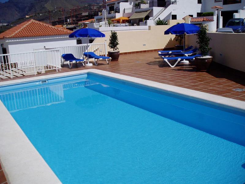 a large blue swimming pool with chairs and umbrellas at Arena Sol in Puerto de Santiago