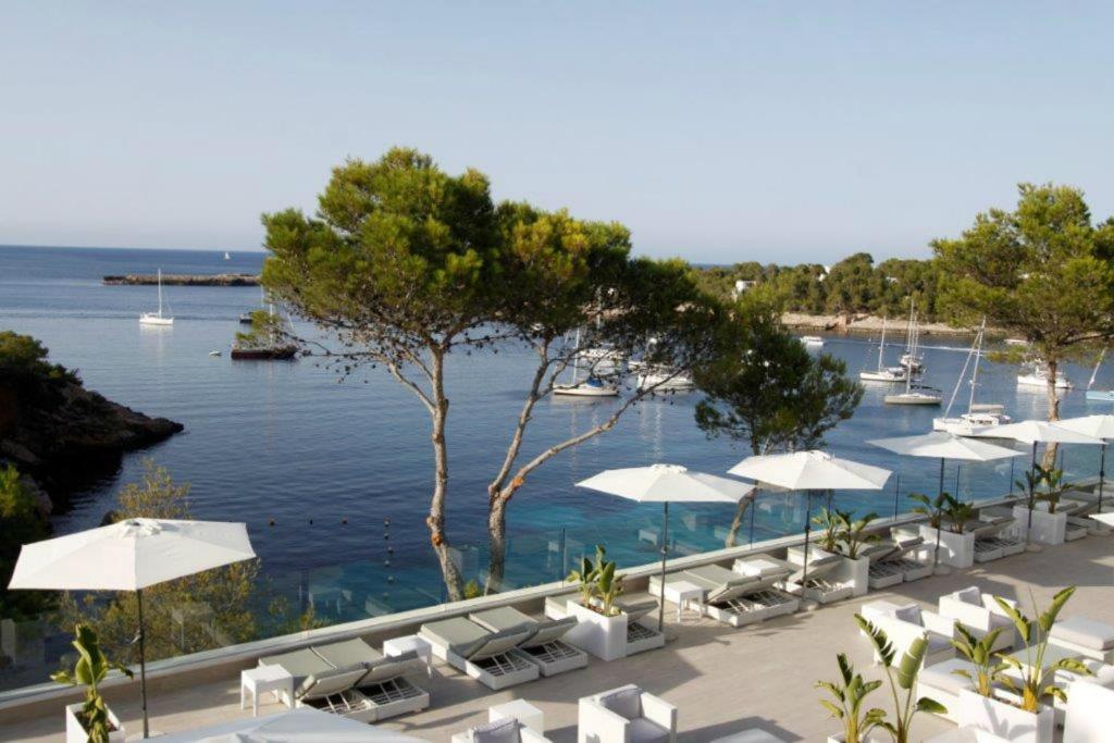 a pool with white umbrellas and chairs and the water at BG Portinatx Beach Club Hotel in Portinatx