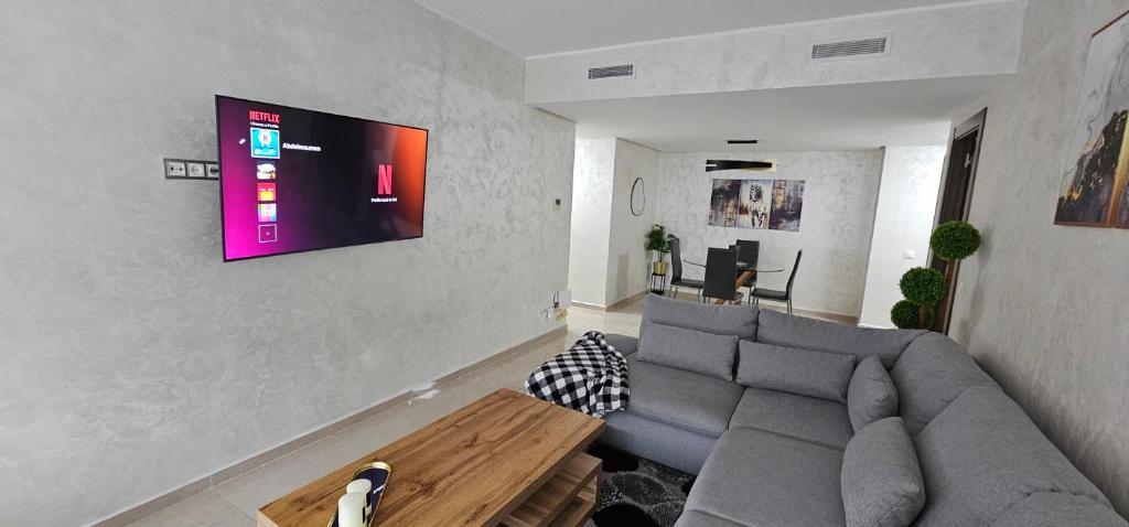 a living room with a couch and a tv on a wall at Luxury apartment near TGV station and the beach in Tangier