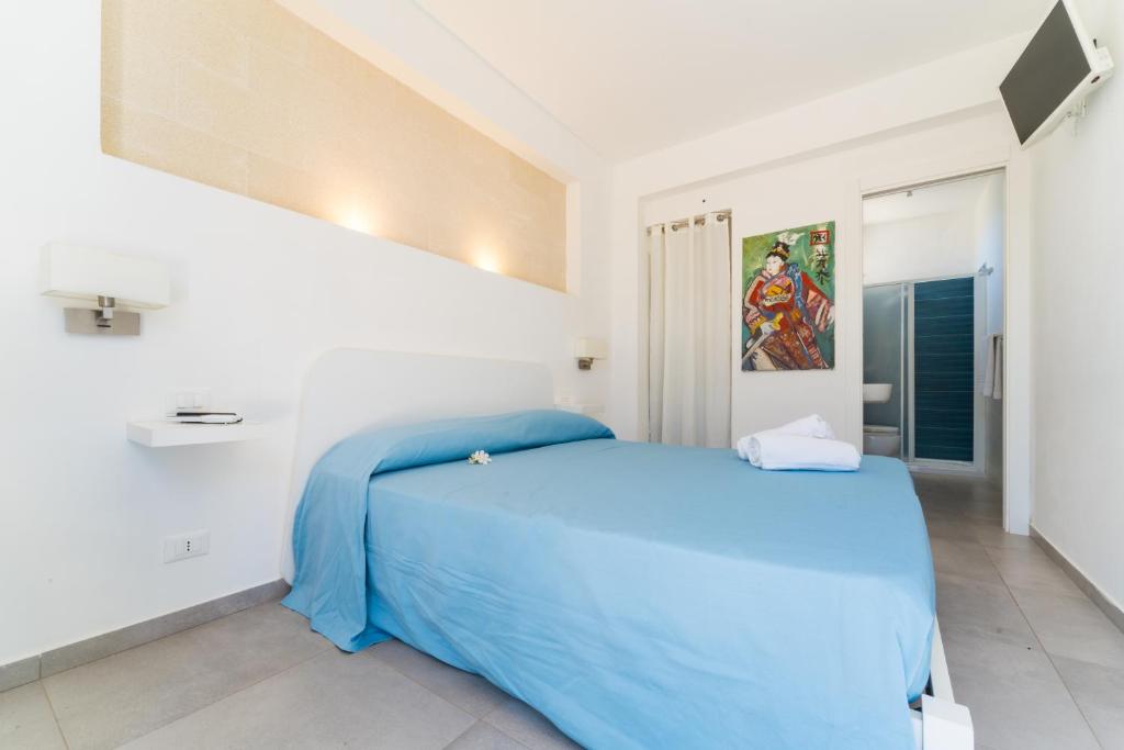 a bedroom with a blue bed in a white room at Villa Gioiello CENTRO in Favignana