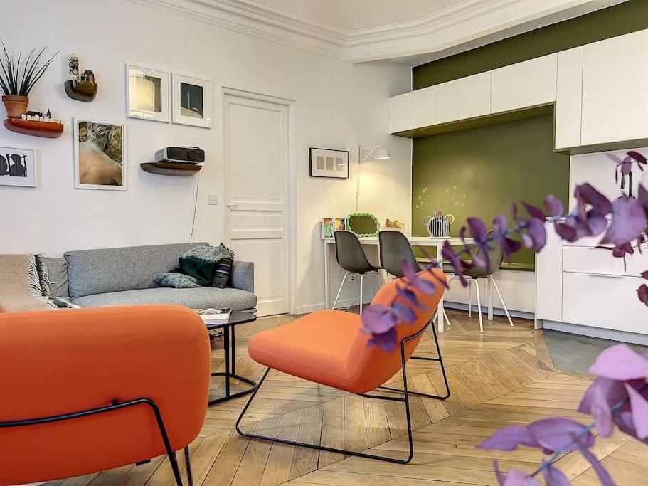 Il comprend un salon avec des chaises orange et une cuisine. dans l'établissement Appartement Art Bougee Montmartre, à Paris
