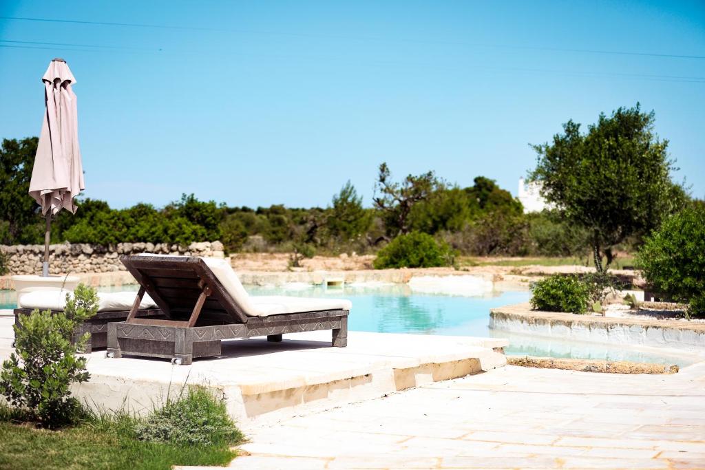 a wooden chair sitting next to a swimming pool at Masseria Piccole Taverne in Rosa Marina