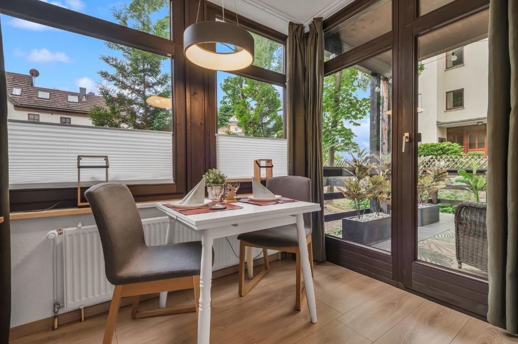 a dining room with a table and chairs and large windows at HIRSCH Stadt Apartment 1 - Terrasse mit Flussblick - Parkplatz in Bad Harzburg
