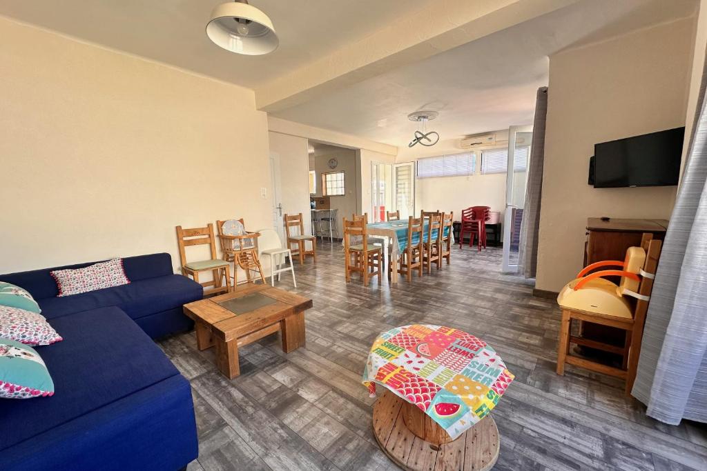 un salon avec un canapé bleu et une salle à manger dans l'établissement COEUR DE CAMARGUE - Terrasse et Garage proche de la Plage, au Grau-du-Roi