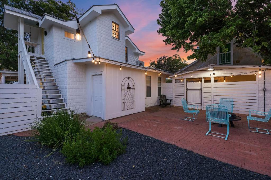a white house with a patio with blue chairs at Stonewall Bungalow 4 - Sleeps 3 in Stonewall