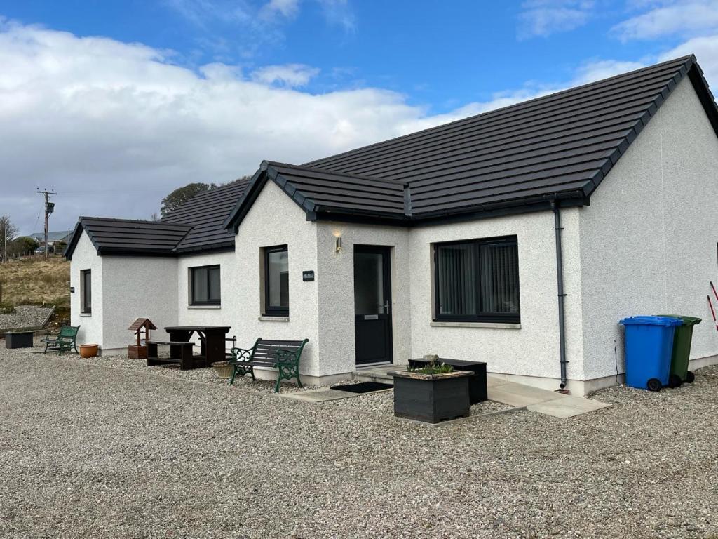 a white house with a black roof at Highland Holiday Lets Lairg in Lairg
