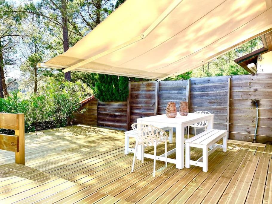 une table et des chaises blanches sur une terrasse en bois dans l'établissement Charmante maison vue sur les pins, à Moliets-et-Maa