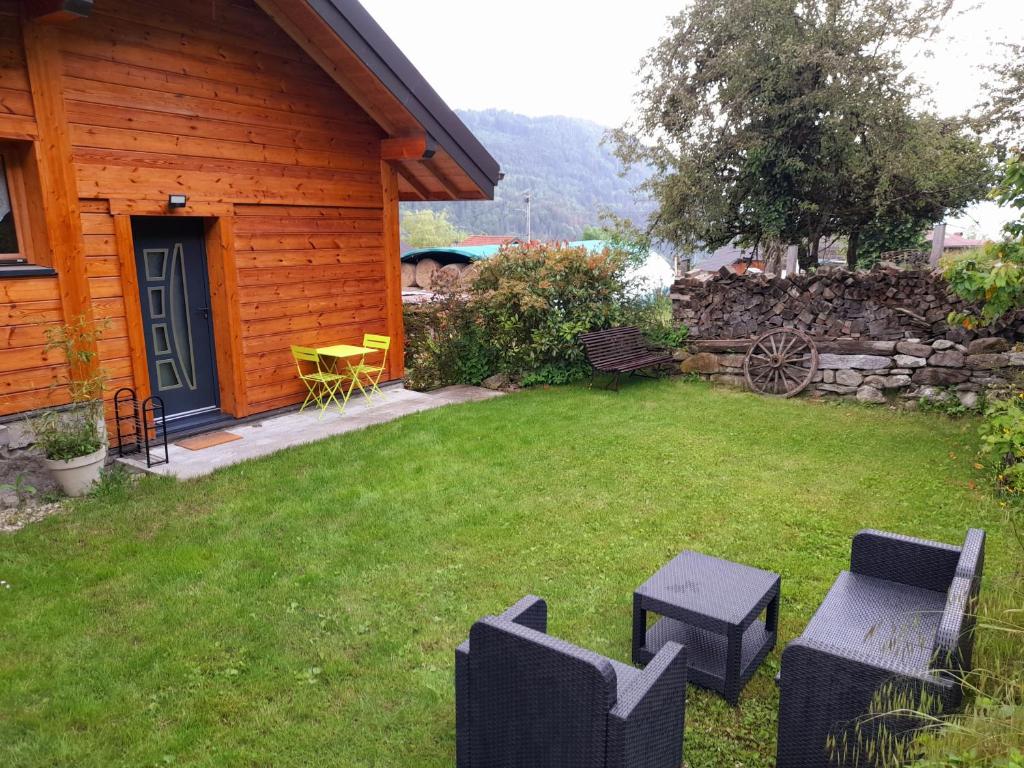 une cour avec des chaises et une cabane en rondins dans l'établissement Demi-chalet à la montagne, à Chevenoz