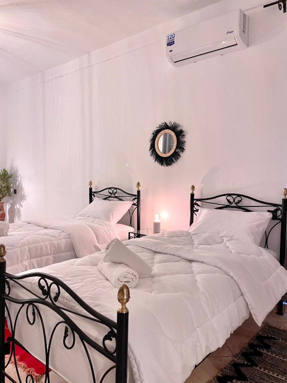 two beds in a white bedroom with a mirror at Dar Bakkali Nadi in Tangier