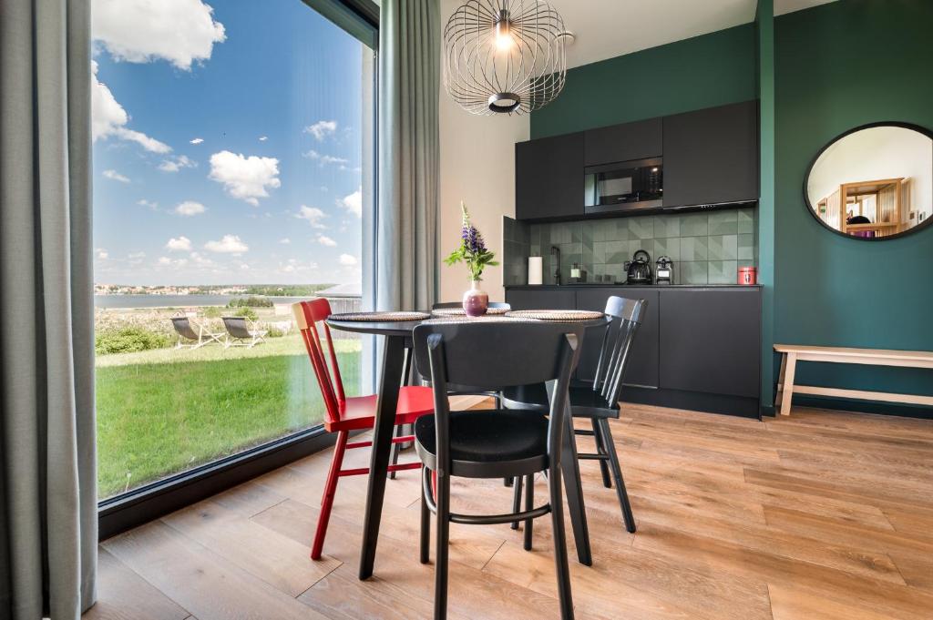 a dining room with a table and chairs and a large window at Luksusowy apartament Ryn Mazury Widok na Jezioro, Gorąca BALIA in Ryn