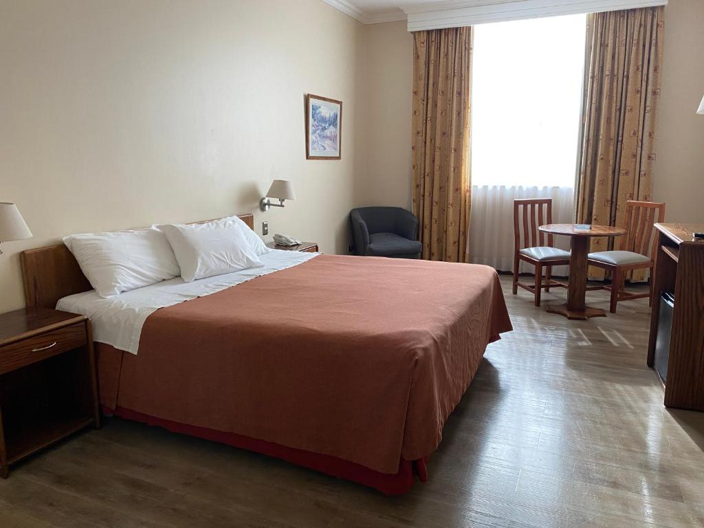 a hotel room with a bed and a table and chairs at Hotel Diego de Almagro Aeropuerto in Santiago