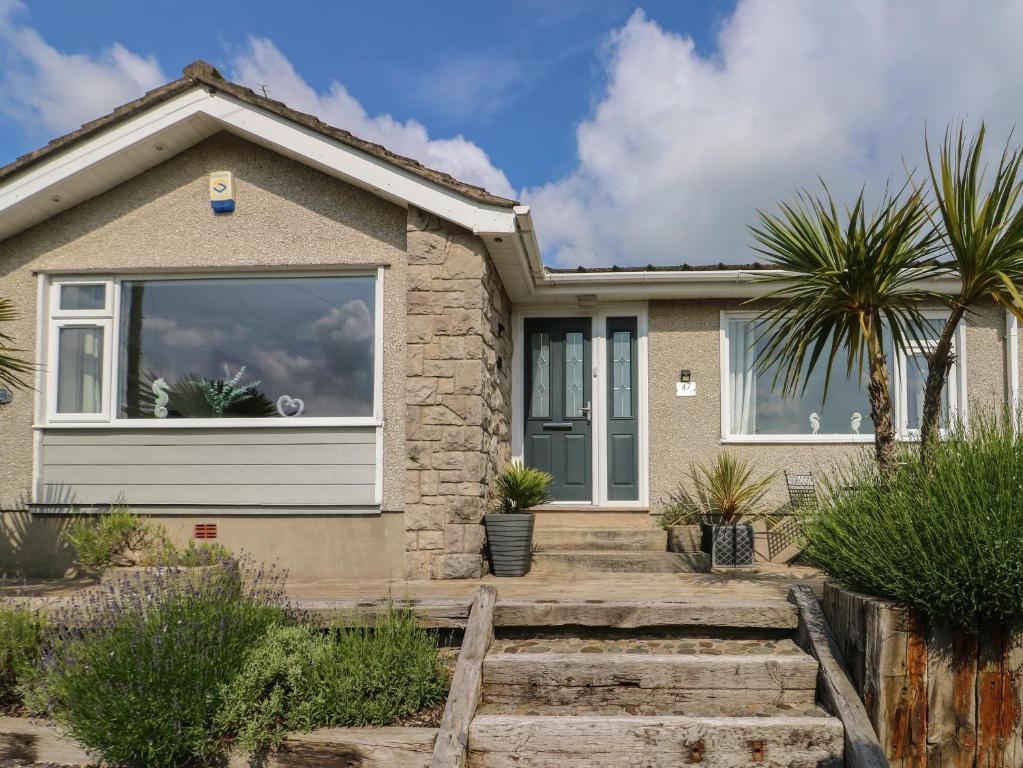 a house with a large window and palm trees at Benllech Bay Cottage in Benllech