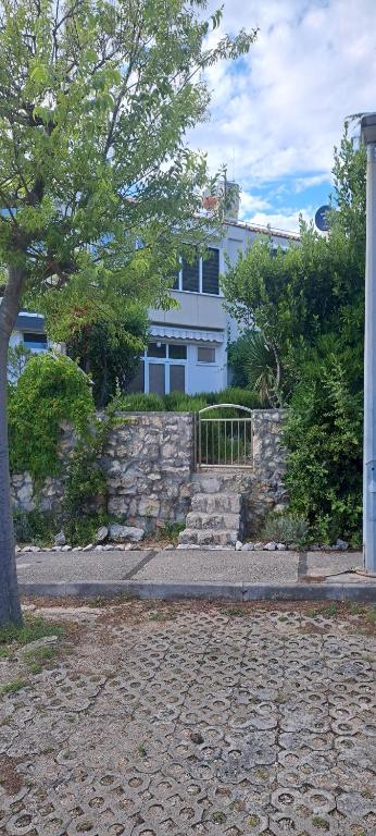 a house with a stone wall and a tree at Apartment Sara M in Gajac