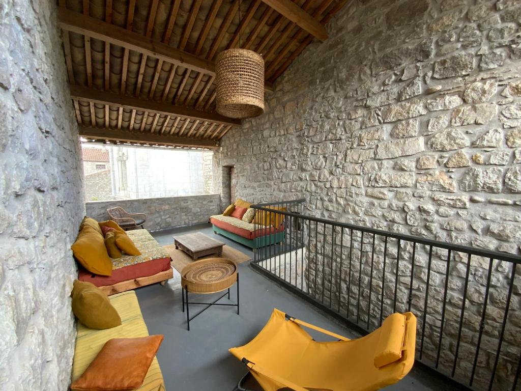 Elle comprend un salon doté d'un mobilier jaune et d'un mur en pierre. dans l'établissement La terrasse suspendue, à Saint Alban Auriolles