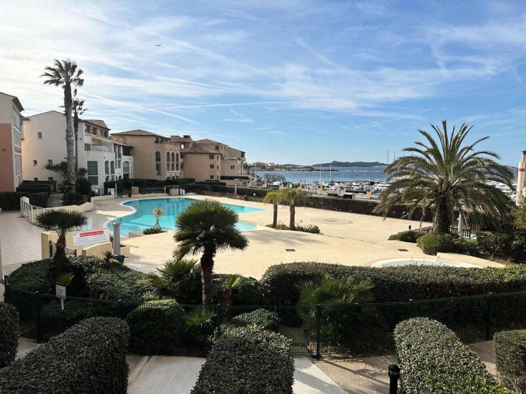 - une vue sur la piscine bordée de palmiers et de bâtiments dans l'établissement Résidence Rivages - Cocktail des îles, joli T2 climatisé avec vue sur piscine et mer dans le domaine de la Coudoulière MAE-0521, à Six-Fours-les-Plages
