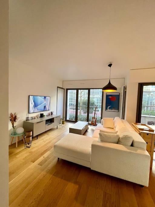 un grand salon avec un grand canapé et une télévision dans l'établissement Modern Bright Lovely Apartment, à Levallois-Perret