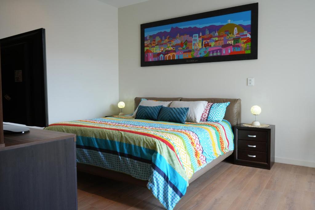 a bedroom with a bed with a painting on the wall at Monoambiente de Lujo Cores in Cochabamba