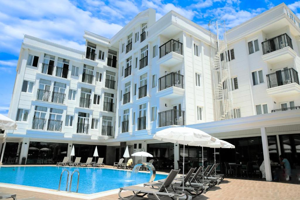 a large white building with a swimming pool and umbrellas at Lara World Hotel in Antalya