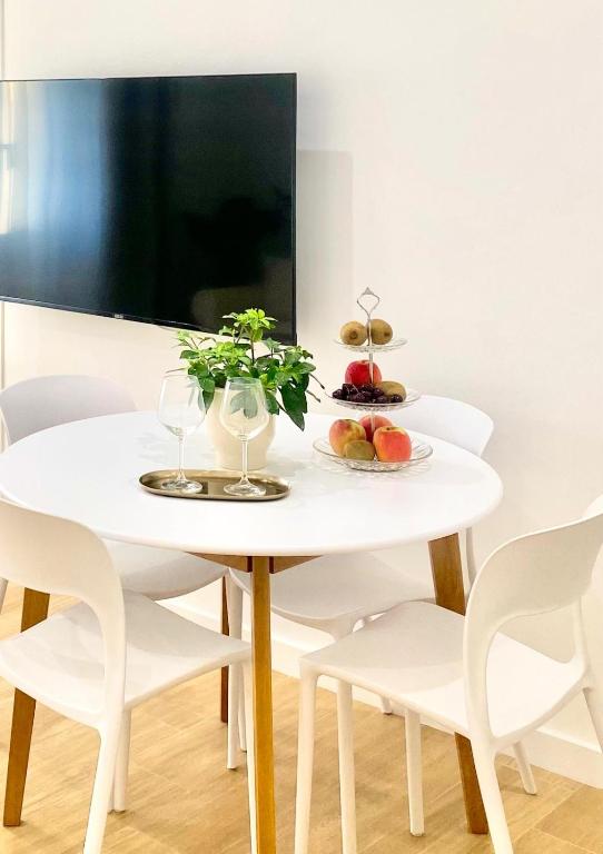 a white table with two glasses and fruit on it at Feel Boutique Rooms in Oristano