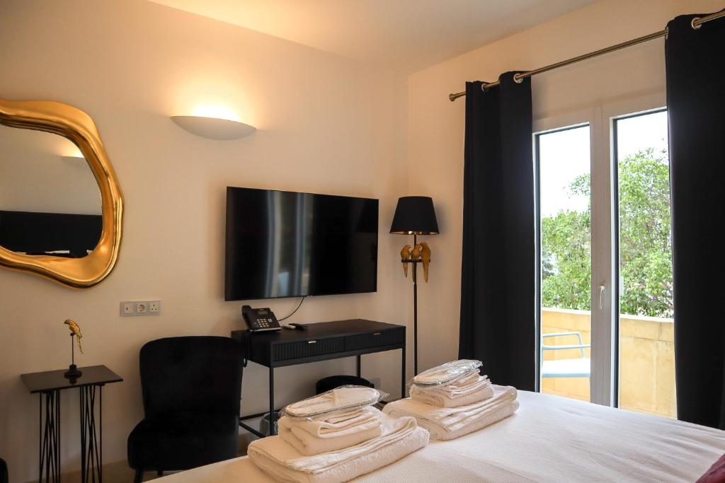 a bedroom with a bed with a television and a chair at The White Knight Premium Boutique Hotel in Għajnsielem