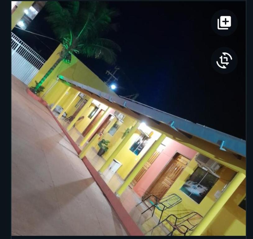a building with chairs and a palm tree at night at Pousada Cristal- Jalapão in Mateiros