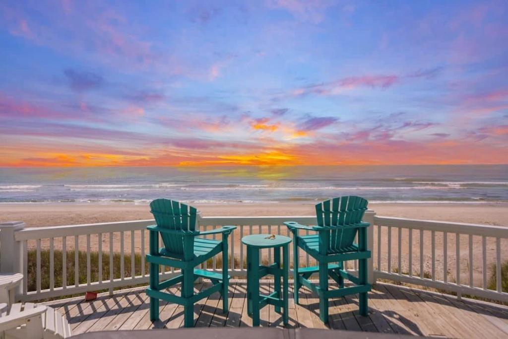 2 stoelen en een tafel op een balkon met uitzicht op het strand bij Topsail Treasure's - Oceanfront Luxury Spa Pool in North Topsail Beach