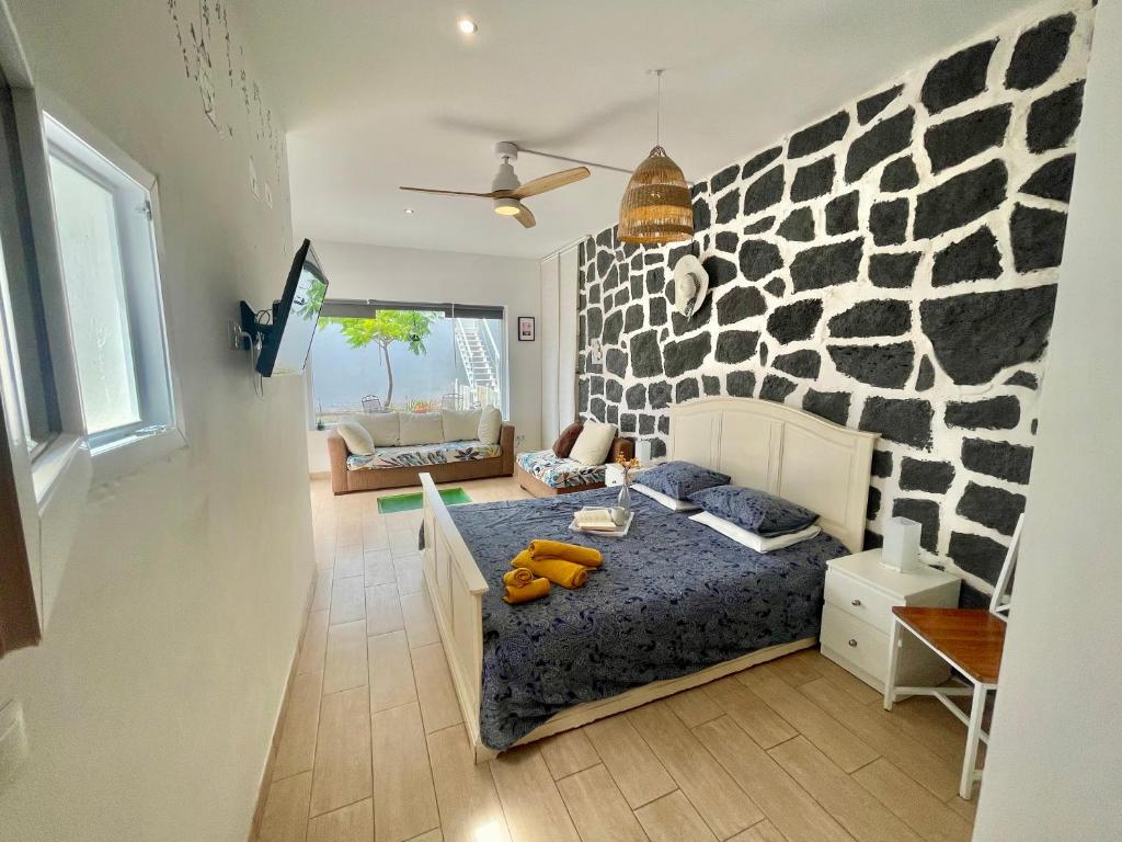 een slaapkamer met een bed en een stenen muur bij Loft La Cueva de los Pájaros in Playa Blanca