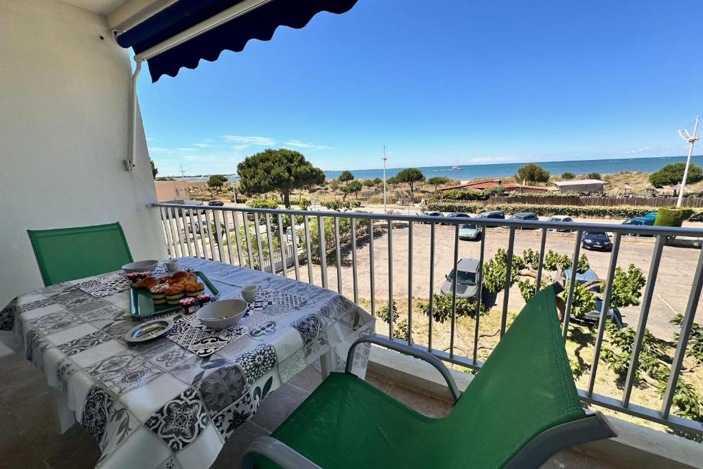 une table et des chaises sur un balcon avec vue sur la plage dans l'établissement DOUCEUR DE MEDITERRANÉE - Vue mer Terrasse et parking, au Grau-du-Roi