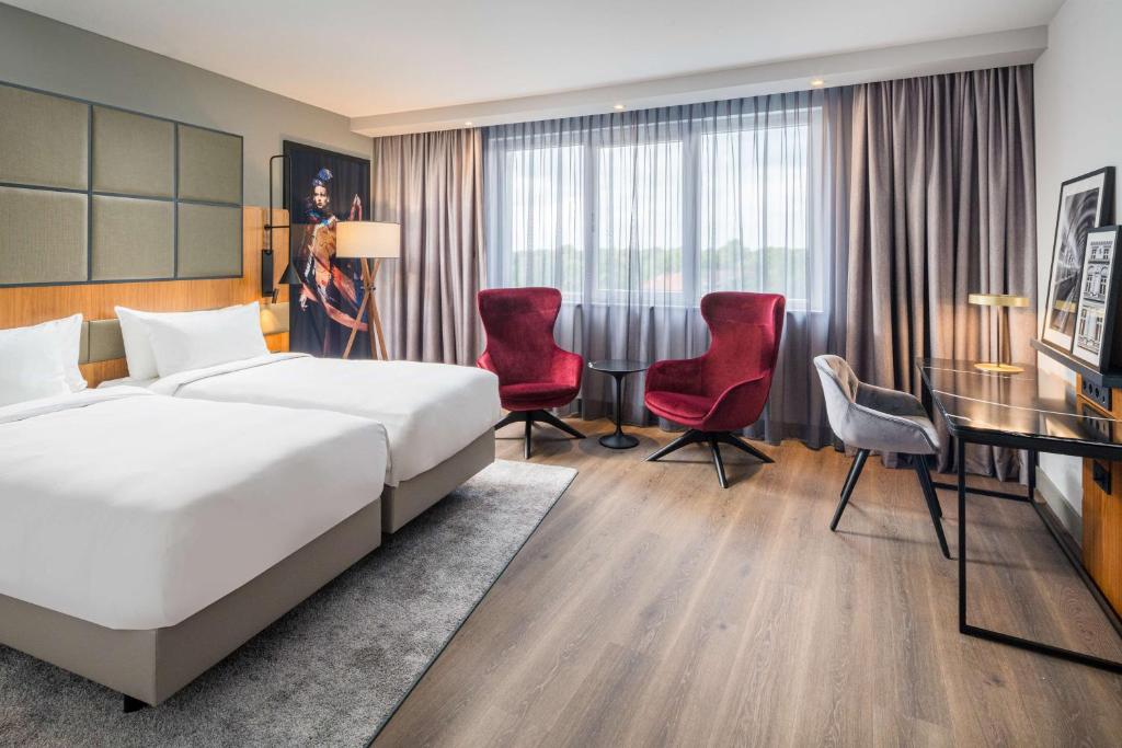 a hotel room with a bed and a desk and chairs at Radisson Blu Hotel, Hamburg Airport in Hamburg