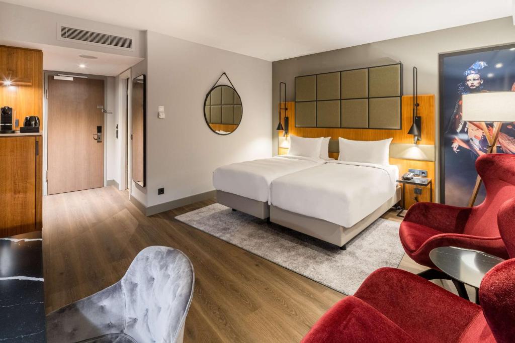 a bedroom with a white bed and red chairs at Radisson Blu Hotel, Hamburg Airport in Hamburg