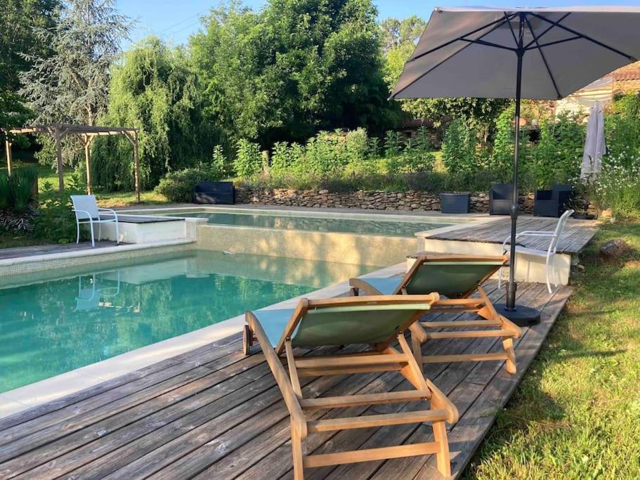 - deux chaises et un parasol à côté de la piscine dans l'établissement La petite maison de Larroque, à Cassagnes