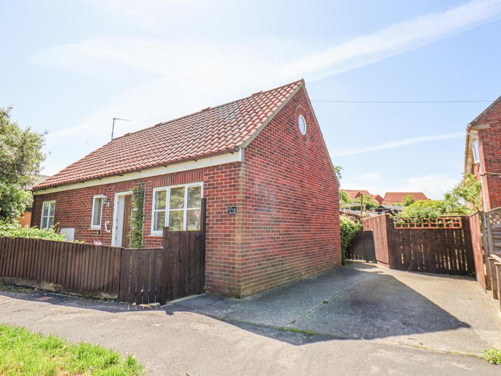 a red brick house with a wooden fence at 1A Police House in Whitby